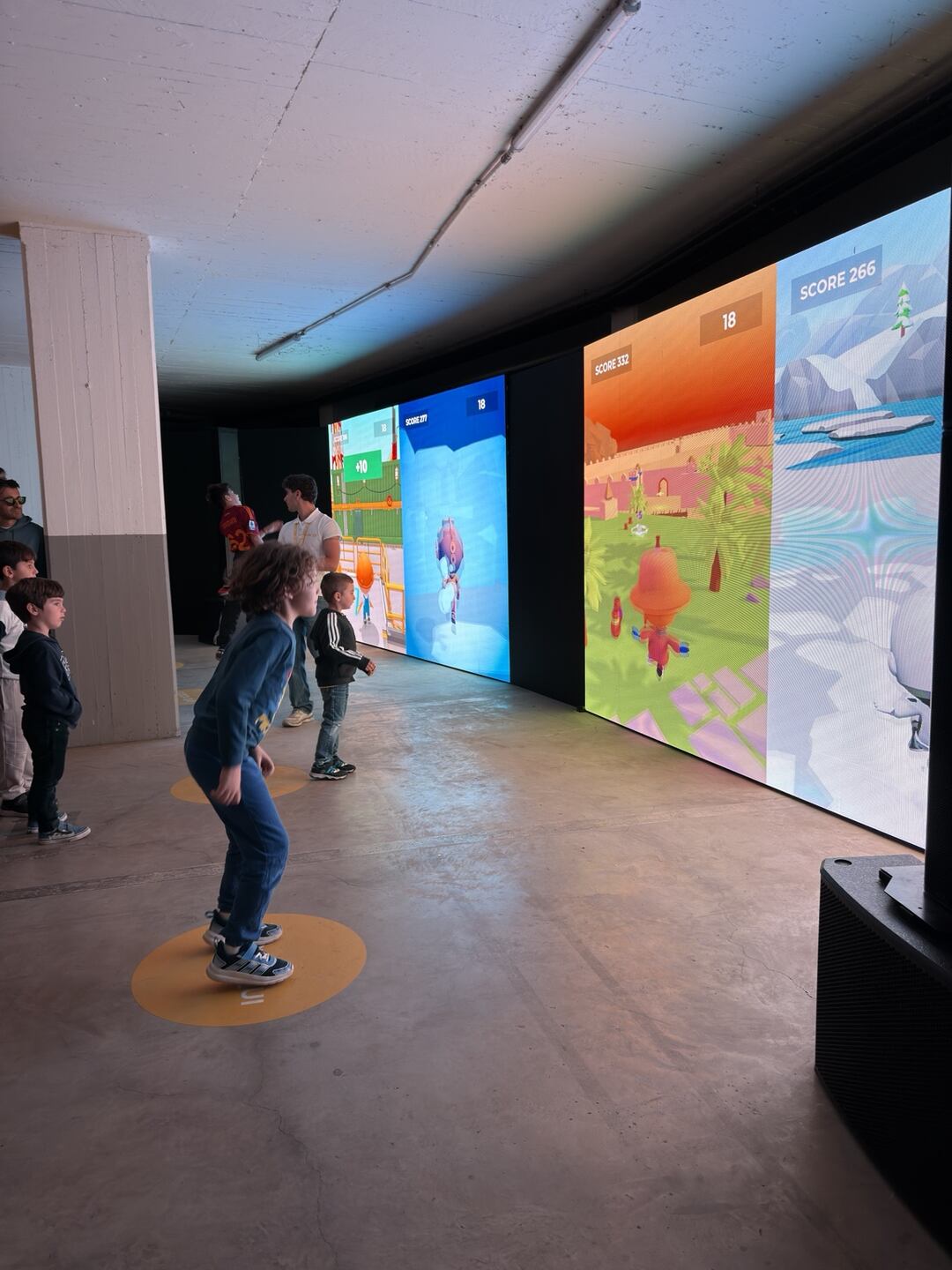 Giovani visitatori provano un&rsquo;installazione di gioco interattivo su grandi schermi. Foto di Claudio Napoli.